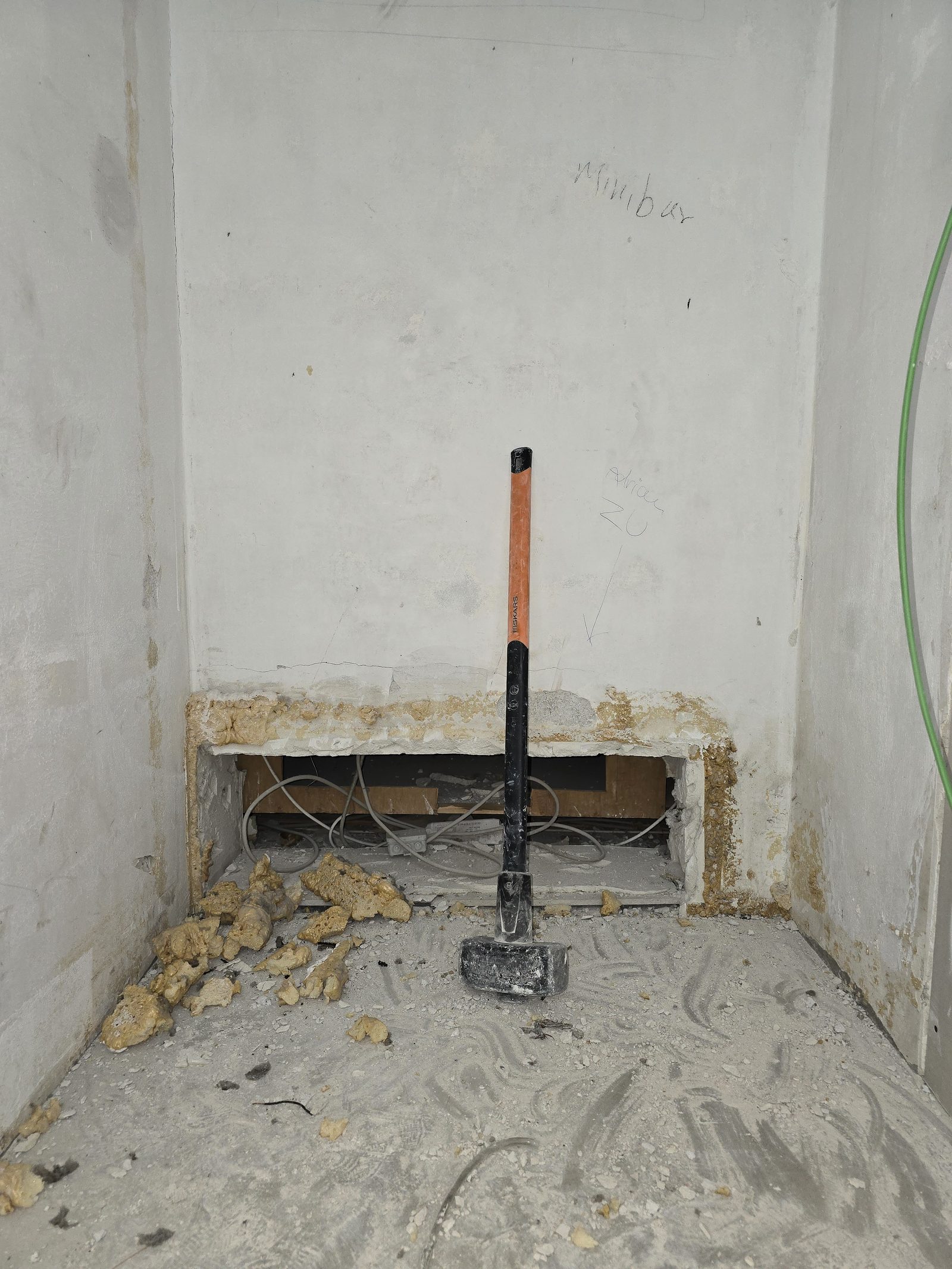 Vorschlaghammer und Schutt in einer geöffneten Wandnische