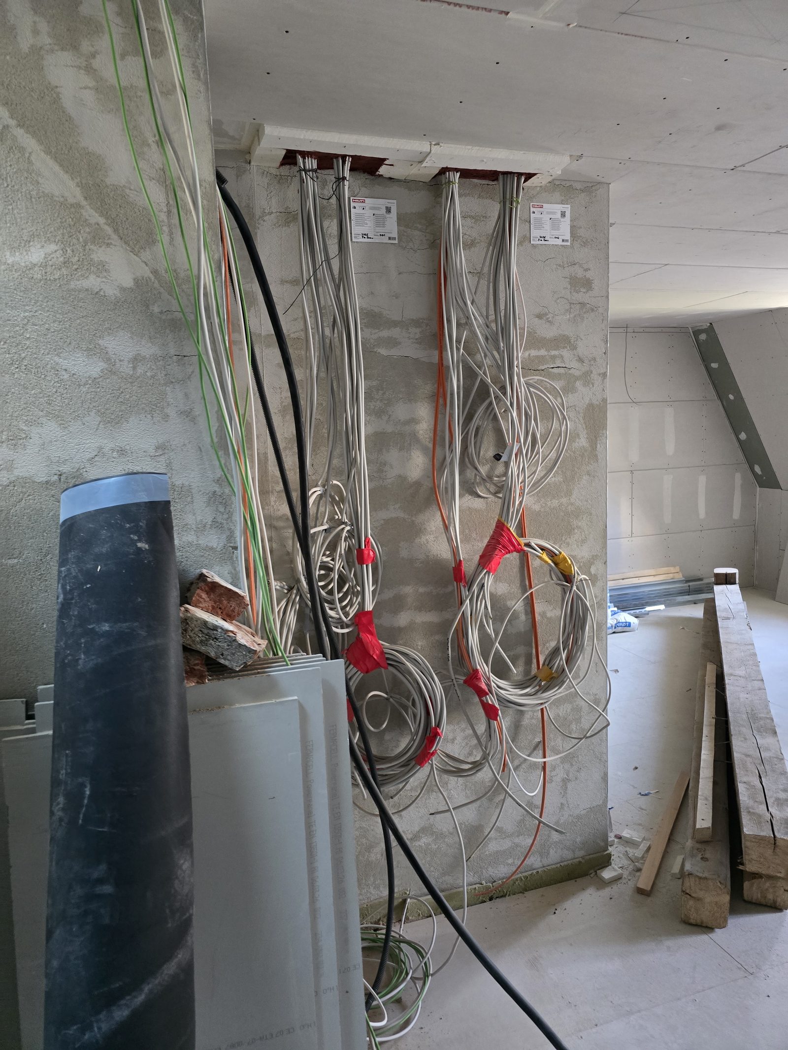 Gebündelte Elektroleitungen an einer Wand im Rohbau