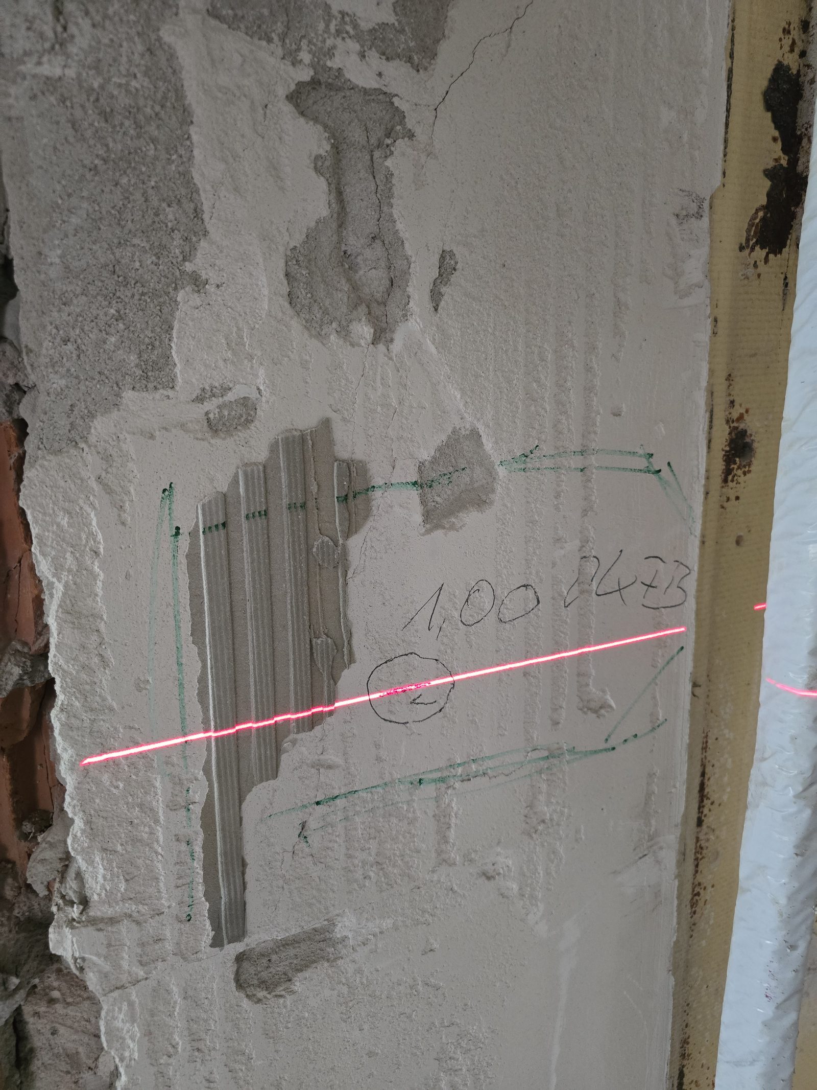 Höhenmarkierung der Bauleitung mit Laserlinie auf einer Baustellenwand